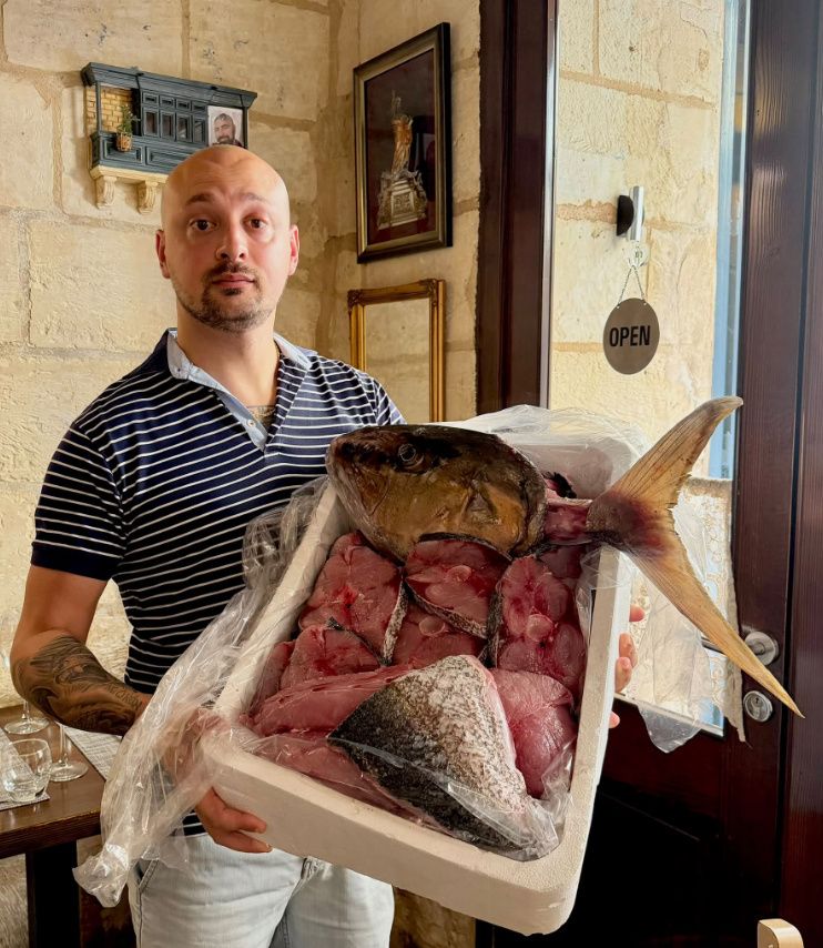 A staff member presenting a fresh whole amberjack