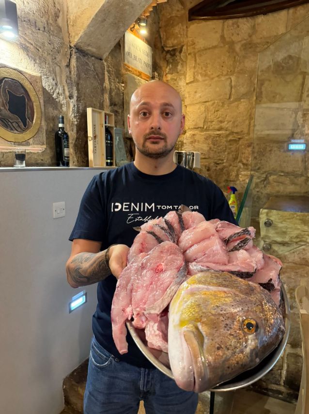 A staff member presenting a fresh whole dentex