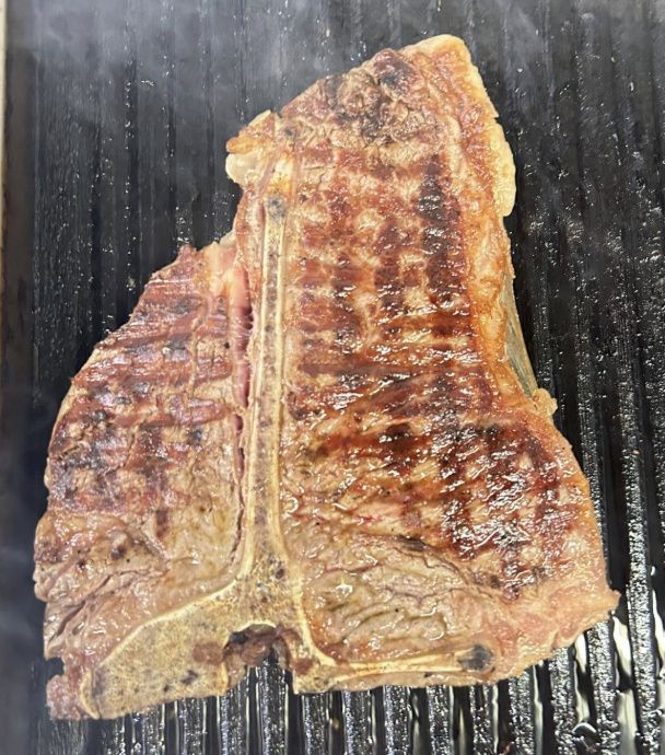 A grilled T-bone steak, charred on the outside
