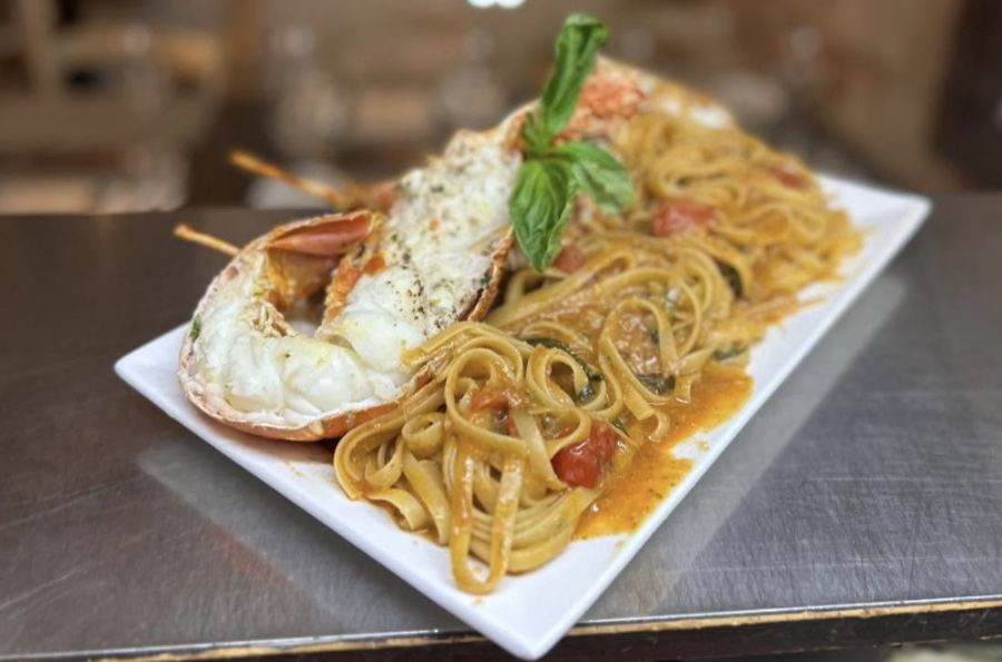 Lobster linguine on a white platter, seen from a low side angle