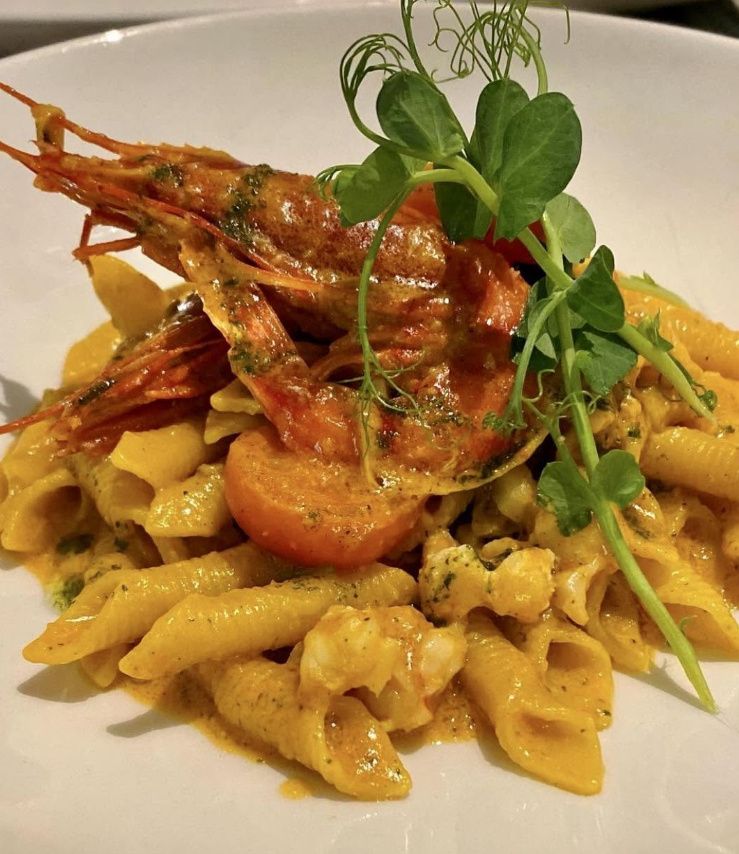 Garganelli pasta in a creamy red prawn sauce, topped with a whole red prawn, cherry tomato and pea shoots