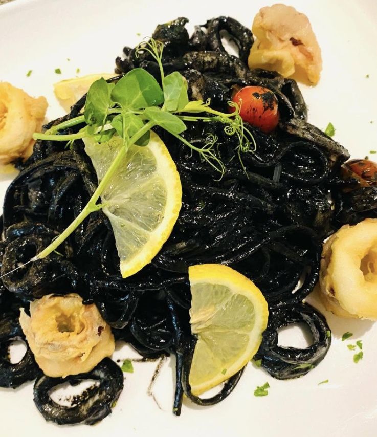 Black squid ink pasta with seafood on a white plate